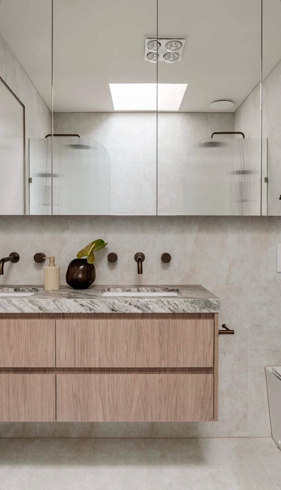 Modern floating bathroom vanity with marble benchtop, timber cabinetry, and mirrored splashback