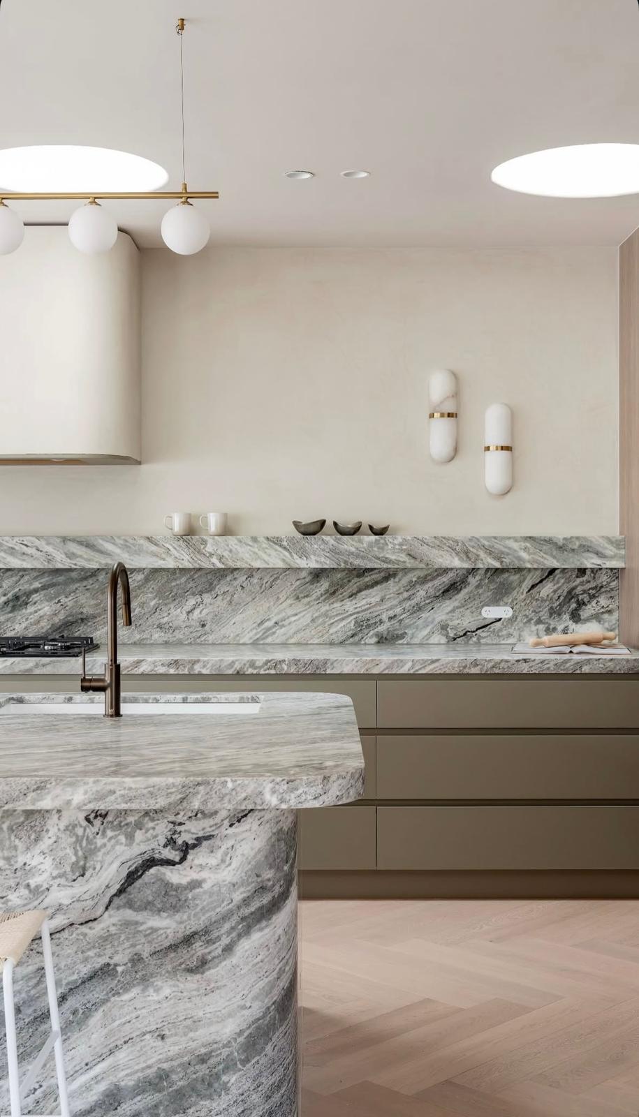 Custom-built kitchen cabinetry with marble benchtop, brass pendant lighting, and herringbone oak flooring